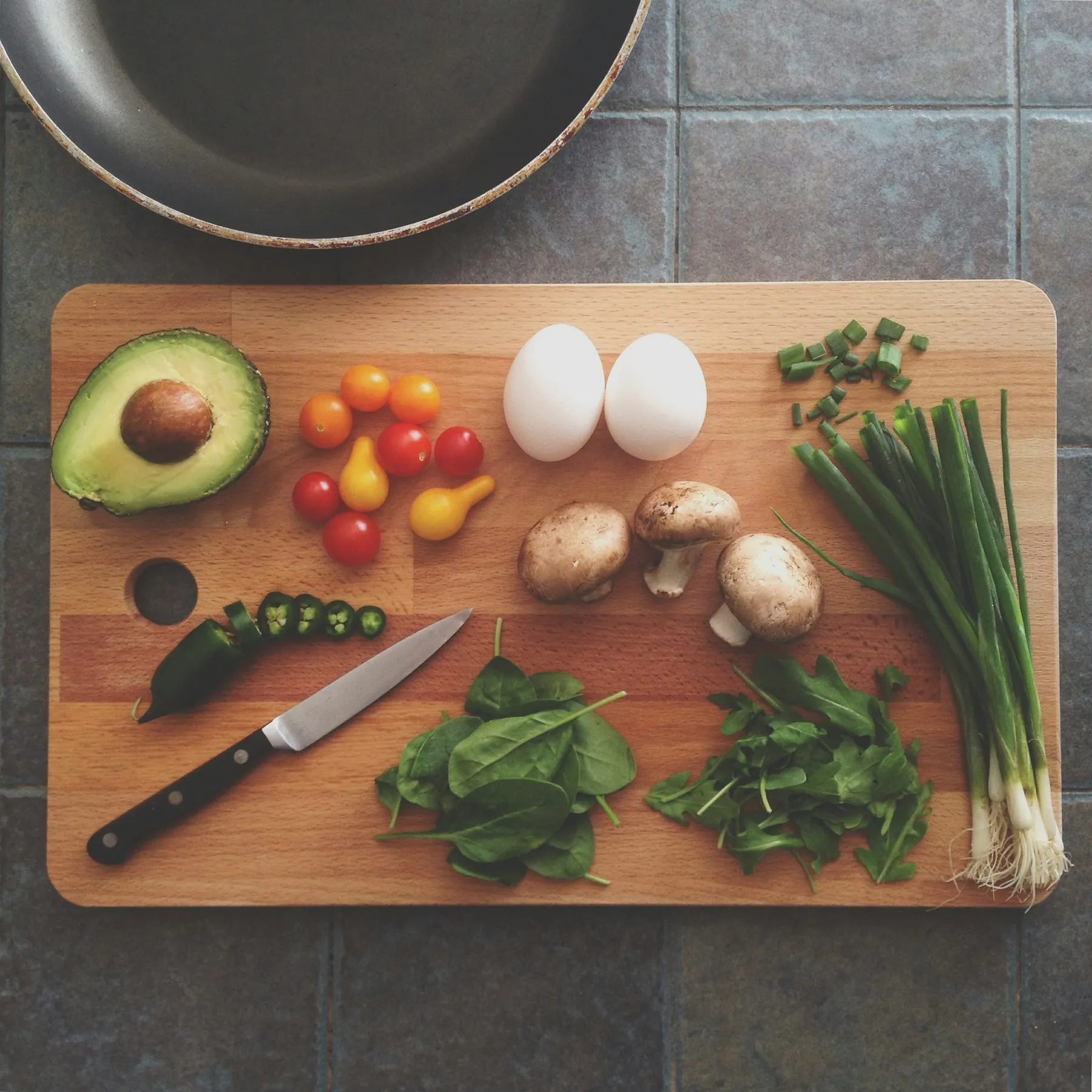 A chopping board of fresh vegetables, eggs and herbs