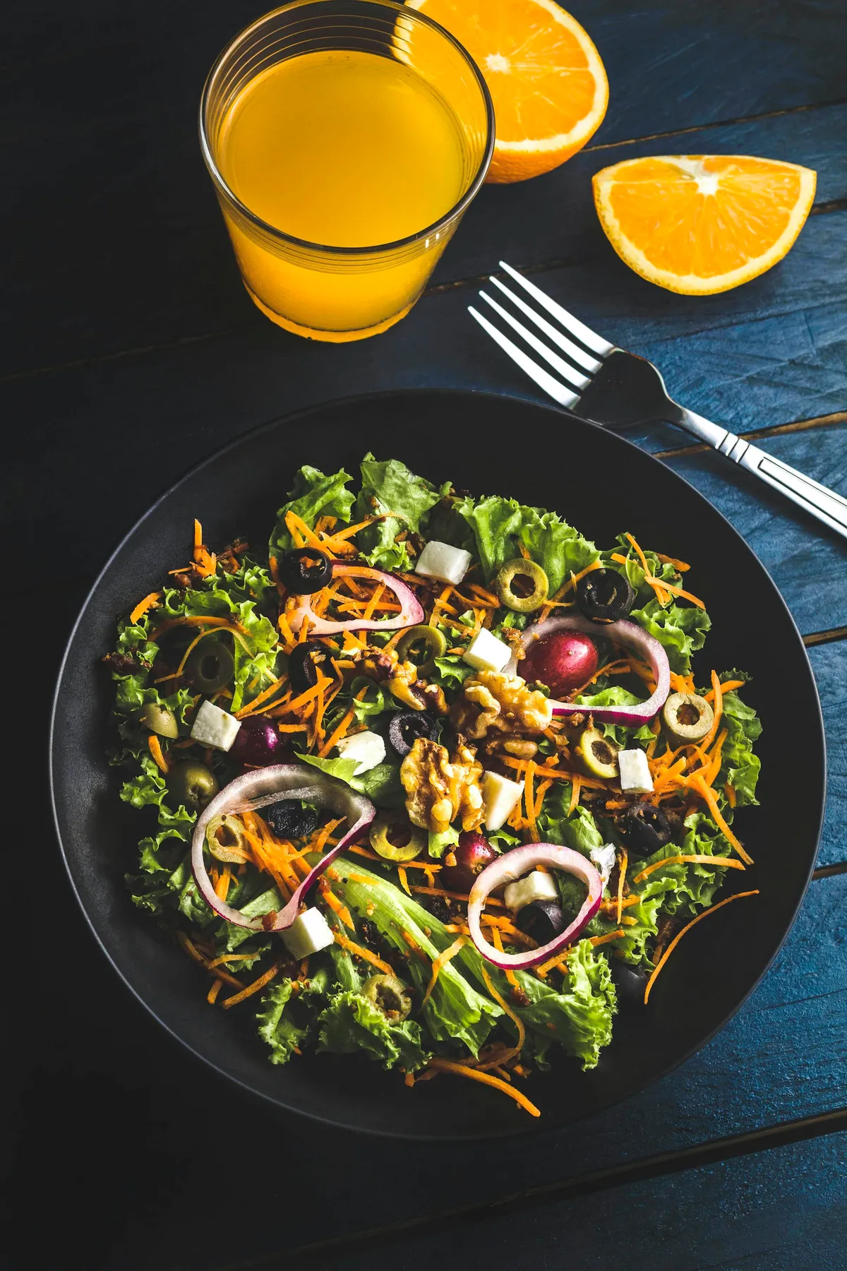 A colourful salad bowl with orange juice